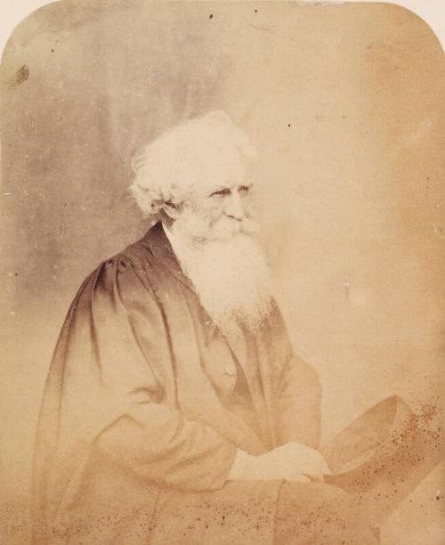 Thomas Combe in Cloak and Holding Mortar Board by Lewis Carroll