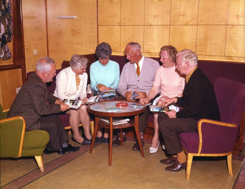 Passengers seated in a lounge aboard St Clair (III) where they are examining North Company broc…