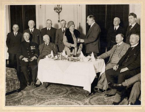 Black and white photograph showing a woman being presented with a teapot at a formal occasion, …