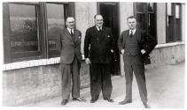 Three Men In Suits Posing Outside The Premises Of Williamson & Co