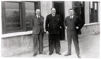 Three Men In Suits Posing Outside The Premises Of Williamson & Co
