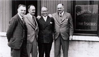 Black and white photograph Showing Four Men In Suits Outside The Premises Of Williamson & Co