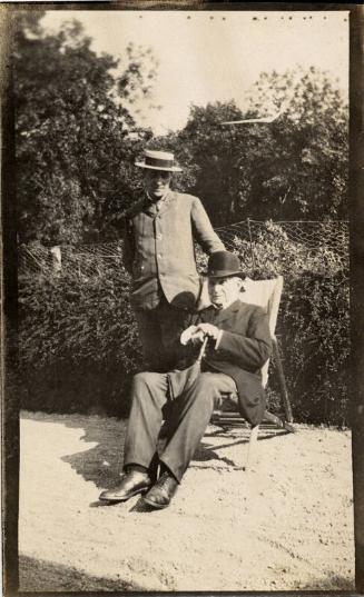 Two Men Wearing Hats, One Seated in Deck Chair