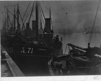 Black and white photograph of Aberdeen Fish Market in the 1920s, fish lying on quayside beside fishing vessels