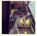 Colour photograph looking down on deck at men working at fish pens
