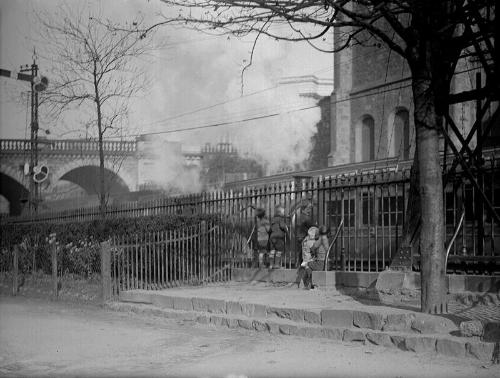 Photograph of children watching, through railings, a passing train at Union Terrace Gardens