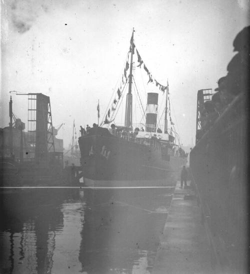 steamship decked in flags entering dock