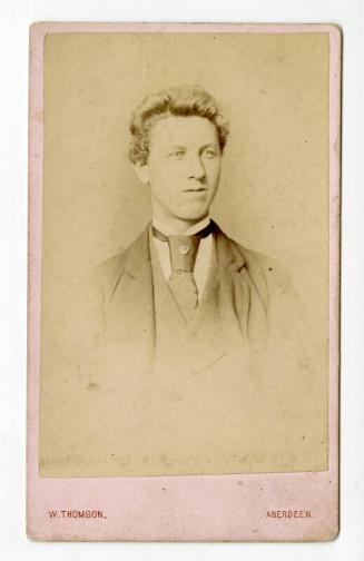 Head and shoulders of young man with wide knot and tie pin