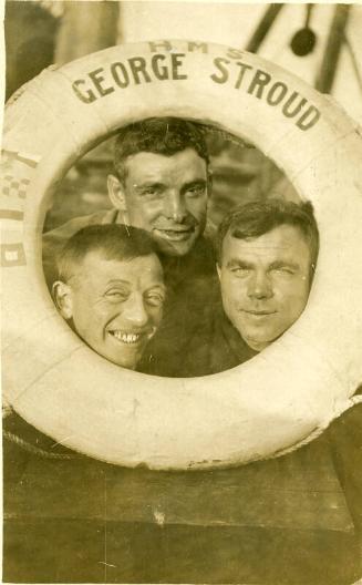 Three men posing with their heads encircled by the lifebelt of the George Stroud