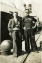 Black & White photograph of Harry Alexander Rumsey and another crew member standing quayside in…