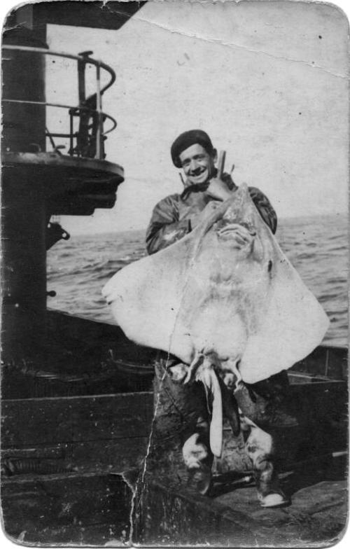 Man holding up large fish on board ship