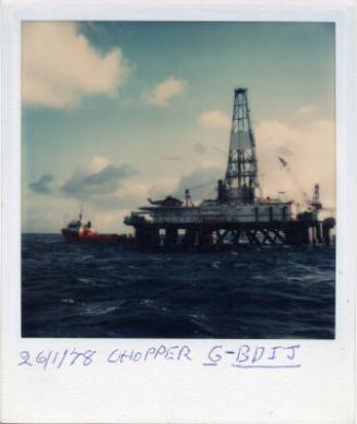 Colour Photograph Showing Helicopter On Deck Of Semi-Sub Rig. Unidentified Supply Vessel In Bac…