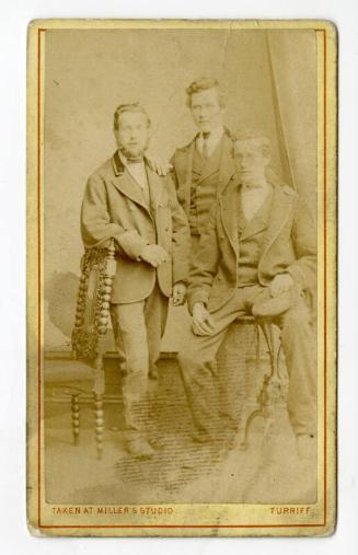 Three young men, one with velvet collar, one seated