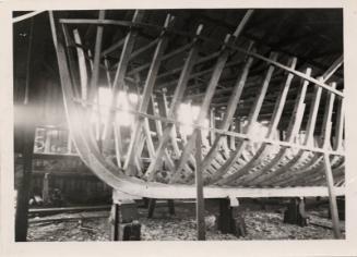 black and white photograph of cabin cruiser under construction