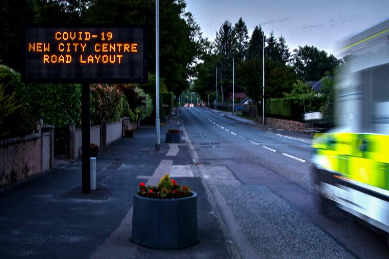 Digital photograph of Illuminated 'stay home and protect lives' sign next to an ambulance