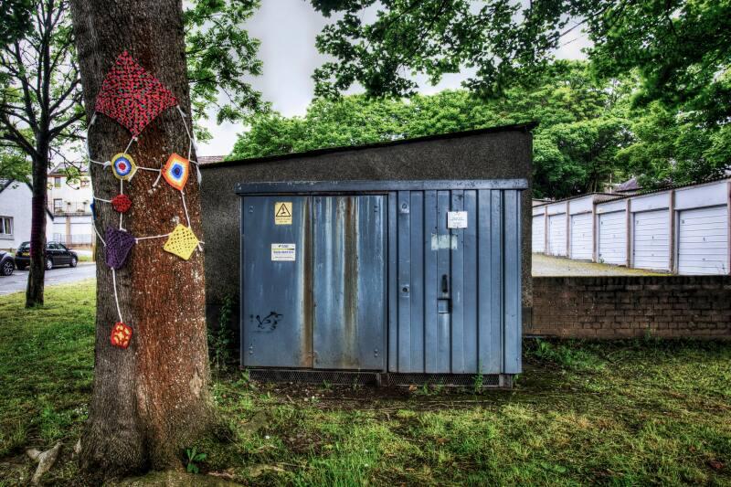 Digital photograph of Colourful knitting around a tree