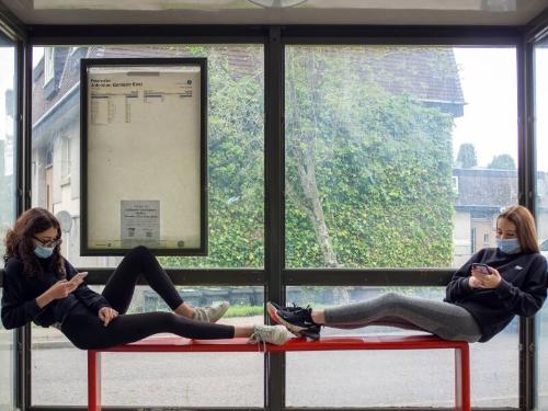 Digital photograph of two teenagers in masks in a bus stop