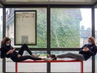 Digital photograph of two teenagers in masks in a bus stop