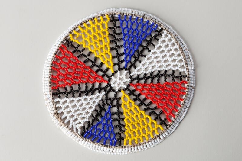 Circular piece of beadwork in white, yellow, red and blue