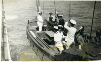 Photograph of men being lowered into boat