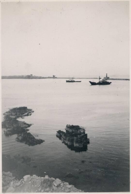 Black and White Photograph in album of ships inside breakwater walls