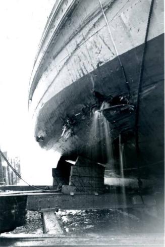 Black and White Photograph in album showing close up of damage to ship's hull