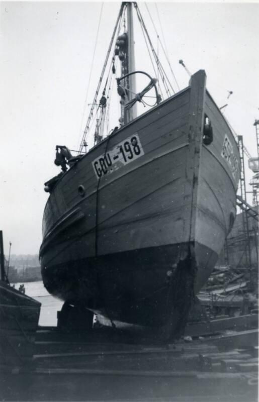 Black and White Photograph in album showing fishing vessel up on stocks in shipyard