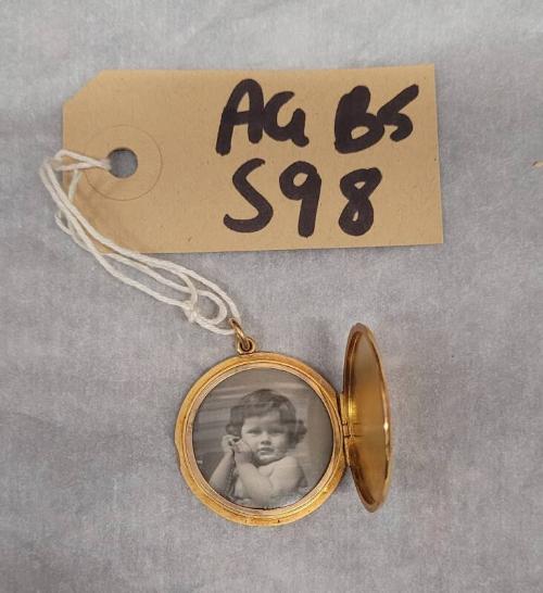 Round Gold Locket Containing a Picture of a Young Girl